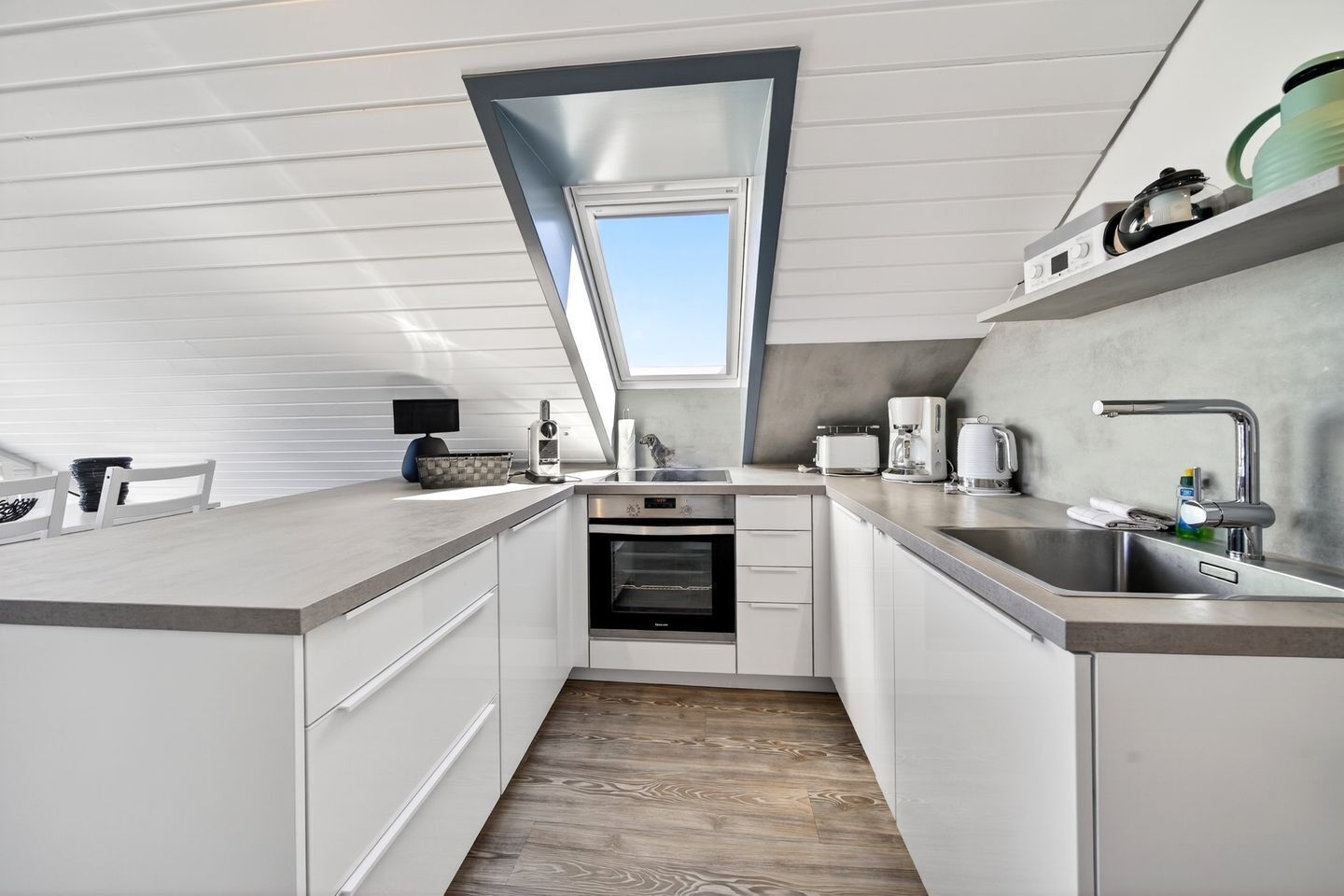 Una cocina moderna con horno empotrado, cafetera y lavabo.