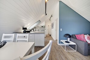 A modern interior with a kitchen, dining area, and a living room with a blue accent wall.