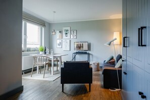 Ein modernes Wohnzimmer mit Essbereich, einer Couch, einem Couchtisch und einem Fernseher.