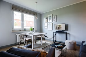 A modern living room with a dining area, a TV, and artwork on the wall.