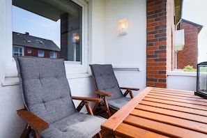 Zwei graue Polsterstühle mit Holzarmlehnen und einem Holztisch.