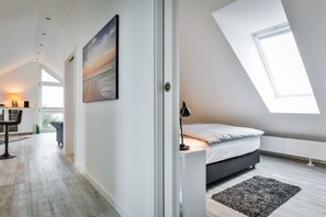 A modern bedroom with a skylight, a bed, a desk, and a chair. - Frisch Sanierte Wohnung in Ruhiger, Strandnaher Lage von Hörnum. - Berliner Ring (Hörnum (Sylt))
