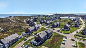 A coastal residential area with modern houses, a road, and a view of the sea. - Frisch Sanierte Wohnung in Ruhiger, Strandnaher Lage von Hörnum. - Berliner Ring (Hörnum (Sylt))