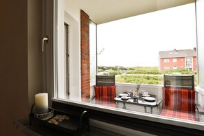 Ein Balkon mit Tisch für zwei Personen, einer Kerze und einem Brotkorb.