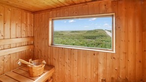 A wooden sauna room with a large window overlooking a grassy landscape. - Beach house - Fantastic detached house under thatch - in the immediate vicinity of the beach. (Hörnum (Sylt))