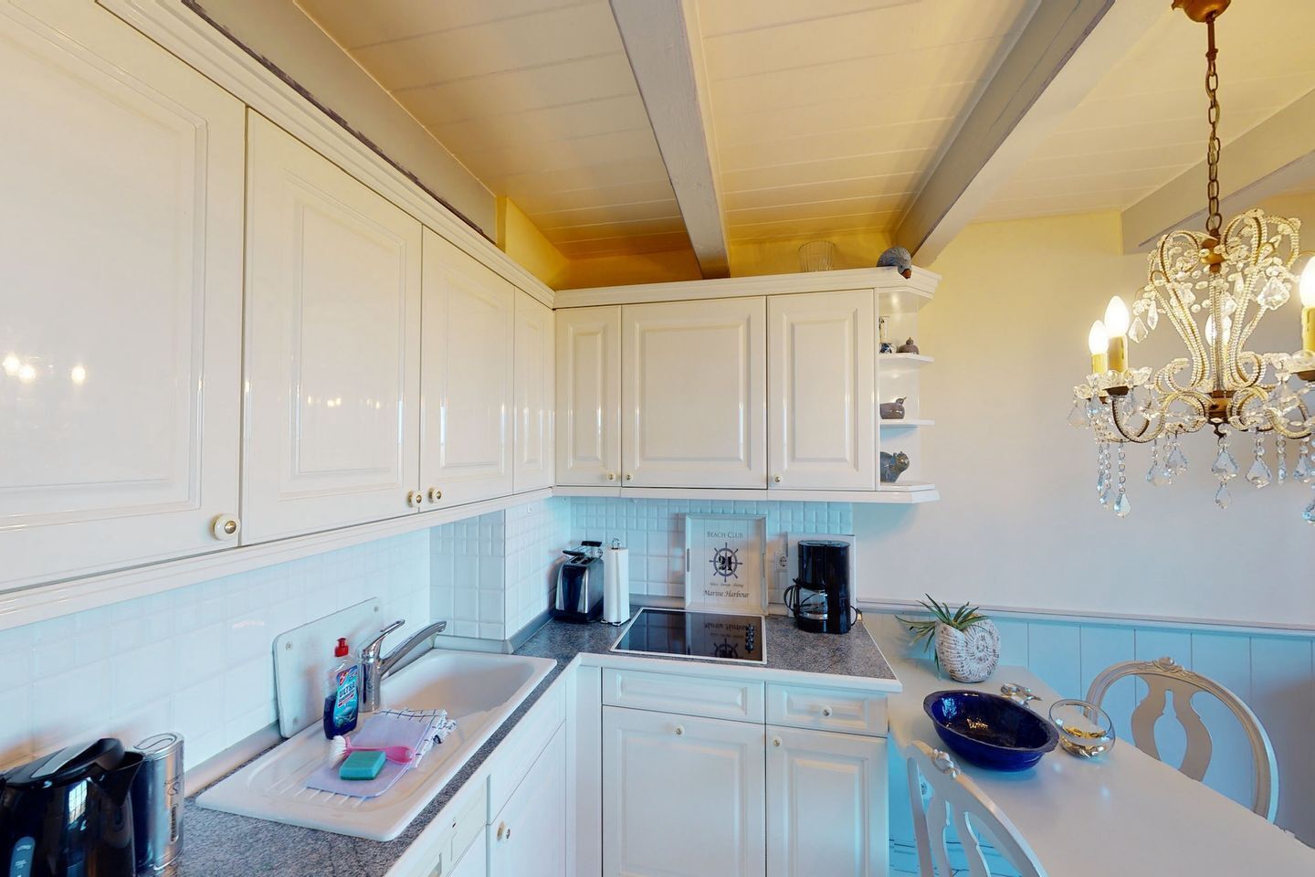A kitchen with white cabinets, a coffee maker, a toaster, and a sink.