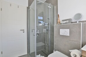 Une salle de bain moderne avec une douche à parois de verre, des toilettes et un lavabo.