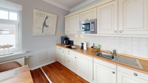 A kitchen with white cabinets, a stainless steel sink, a microwave, and a coffee maker.