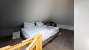 A bedroom with a bed, nightstands, a wooden headboard, and a patterned rug.