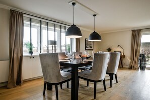 A dining area with a round table, six chairs, and two pendant lights. - Lornsendüne - Modern apartment in an absolutely beachfront location in Westerland with (Sylt)