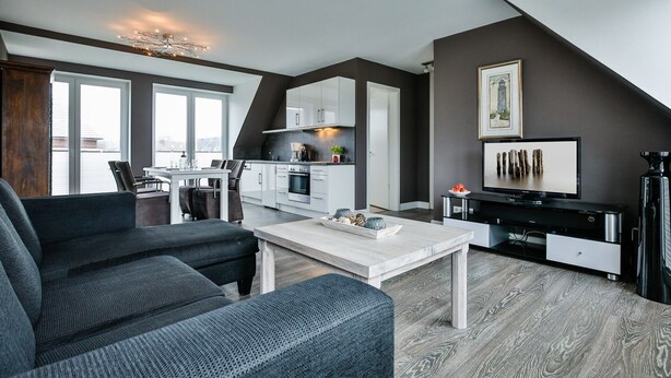 Een moderne woonkamer met een grijze bank, een witte salontafel en een tv-meubel met een flatscreen televisie.