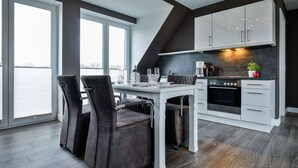 Een moderne keuken met een eethoek, grote ramen en uitzicht op de stad.