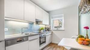 A modern kitchen with white cabinets, stainless steel appliances, and a window above the sink.
