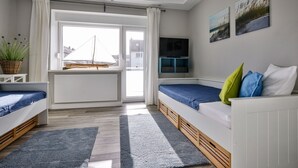 Ein modernes Schlafzimmer mit zwei Betten, einem Fernseher und einem großen Fenster mit Blick auf eine Brücke.