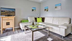 Ein modernes Wohnzimmer mit einem beigen Sofa, einem Glastisch und einer Holzkabine.