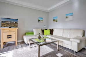 A modern living room with a beige sofa, a glass coffee table, and a wooden cabinet.