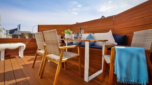A wooden deck with a table and chairs, a bench, and a sofa with cushions. - Njørd - Haus Möwe, Deutschland (Hörnum (Sylt))