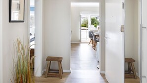 A hallway with wooden flooring, a small wooden stool, and a potted plant. - Njørd - Haus Möwe, Deutschland (Hörnum (Sylt))