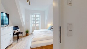 A bedroom with a bed, a desk, a chair, a TV, and a window. - Ellis beach house Sylt (Hörnum (Sylt))