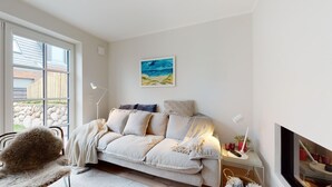 A cozy living room with a sofa, a painting, and a TV. - Ellis beach house Sylt (Hörnum (Sylt))