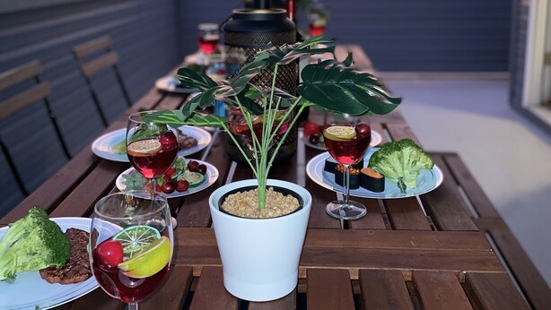 Una mesa de comedor con diversos platos, bebidas y una planta en maceta.