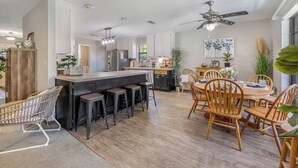 A modern kitchen with a central island, bar stools, wooden dining table, and chairs. - Lake Palo Pinto Home w/ Dock: 22 Mi to State Park! (Palo Pinto)