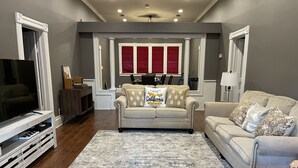 Ein Wohnzimmer mit einem beigen Sofa, einem Fernseher und einem Couchtisch.