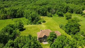 Une maison entourée d’une végétation luxuriante et située dans un paysage vallonné.