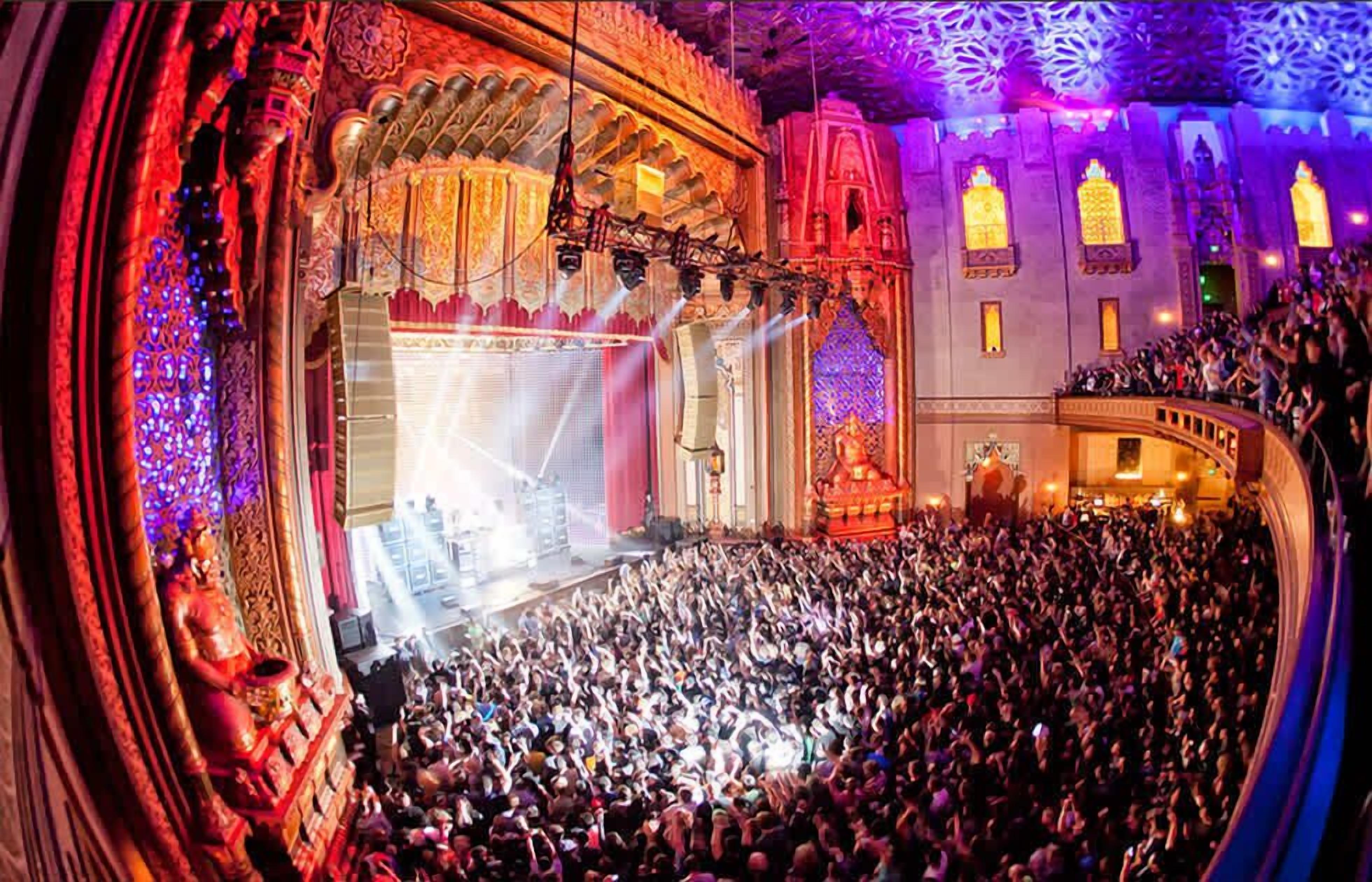 A crowded theater with ornate architecture and a large audience.