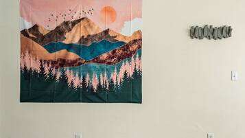 A tapestry with a mountainous landscape and birds, displayed on a wall.