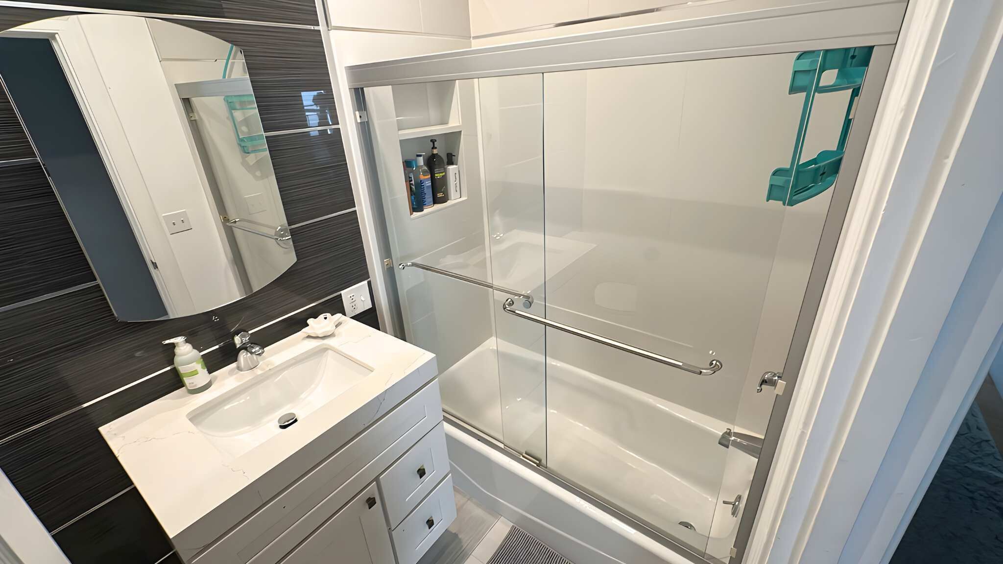 A modern bathroom with a glass shower enclosure, a white sink, and a mirror.