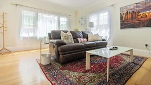 Una sala de estar moderna con un sofá de cuero, una mesa de centro de vidrio y un tapete estampado.