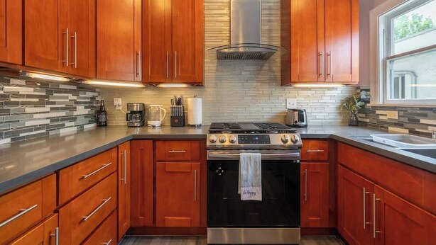 Una cocina moderna con armarios de madera, estufa de acero inoxidable y salpicadero de azulejos.