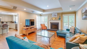 A spacious living area with a sofa, a glass coffee table, and a television. There is a kitchen area with cabinets and a dining table. - Pool, Hot Tub & Outdoor Theater: Franklin Retreat (Franklin)