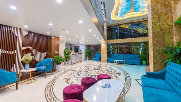 Un vestíbulo moderno con una zona de estar central, un mostrador de recepción y un techo decorativo.