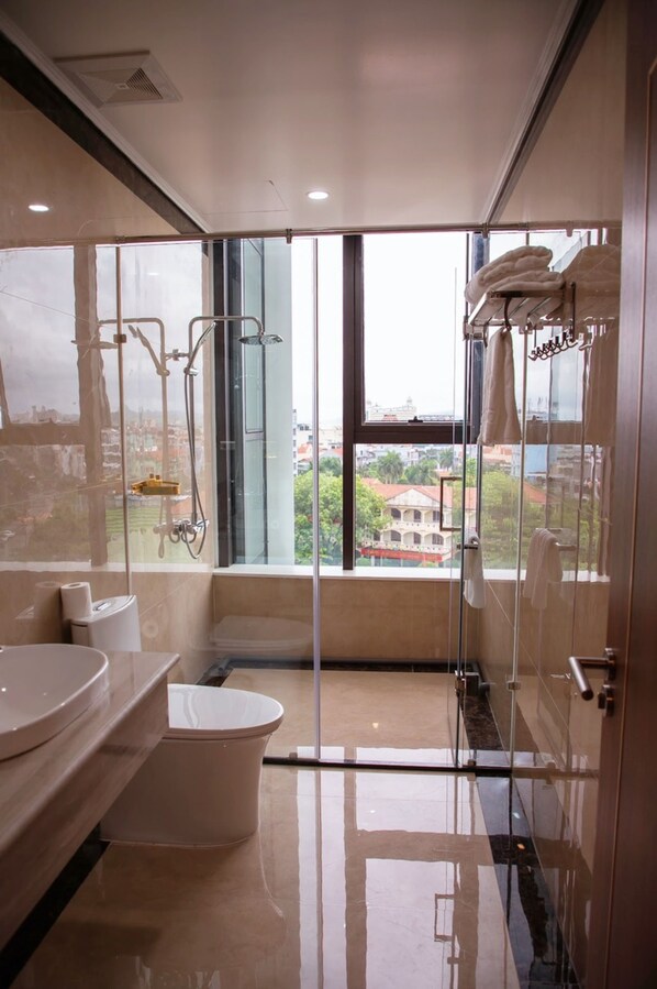 A modern bathroom with a glass shower enclosure, a toilet, and a sink.