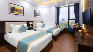 Habitación de hotel con dos camas, un escritorio, televisión y vista a la ciudad.