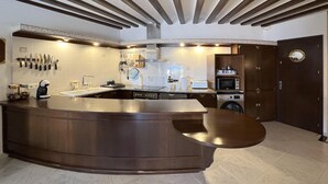 A modern kitchen with a curved island, built-in appliances, and a dark wood finish. - Rental apartment with sea view in Aiguafreda, Begur (Begur)