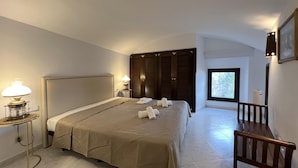 A hotel room with a large bed, a bedside table with a lamp, a wooden chair, and a window with a view of greenery. - Rental apartment with sea view in Aiguafreda, Begur (Begur)