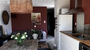 Une cuisine moderne avec des armoires blanches, un four à micro-ondes encastré et une hotte de cuisinière en acier inoxydable.