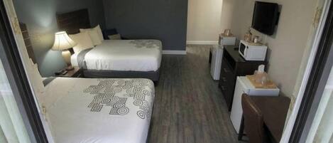 A hotel room with two beds, a desk, a chair, a television, and a microwave.