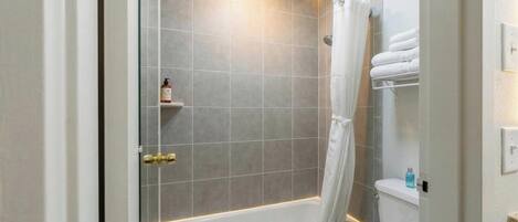 A modern bathroom with a shower, toilet, and a towel rack.
