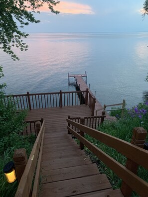 Un escalier en bois mène à une jetée surplombant une étendue d’eau calme.