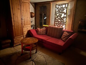 A cozy living room with a red sofa, a small wooden table, and a patterned rug.