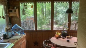 Una cocina rústica con armarios de madera, un lavamanos, una estufa y una ventana con vistas a un bosque.