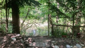 Un sendero de piedra que atraviesa un área boscosa, con un estanque al fondo.