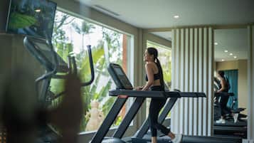 A gym with treadmills, a large window with a view of greenery, and a statue.