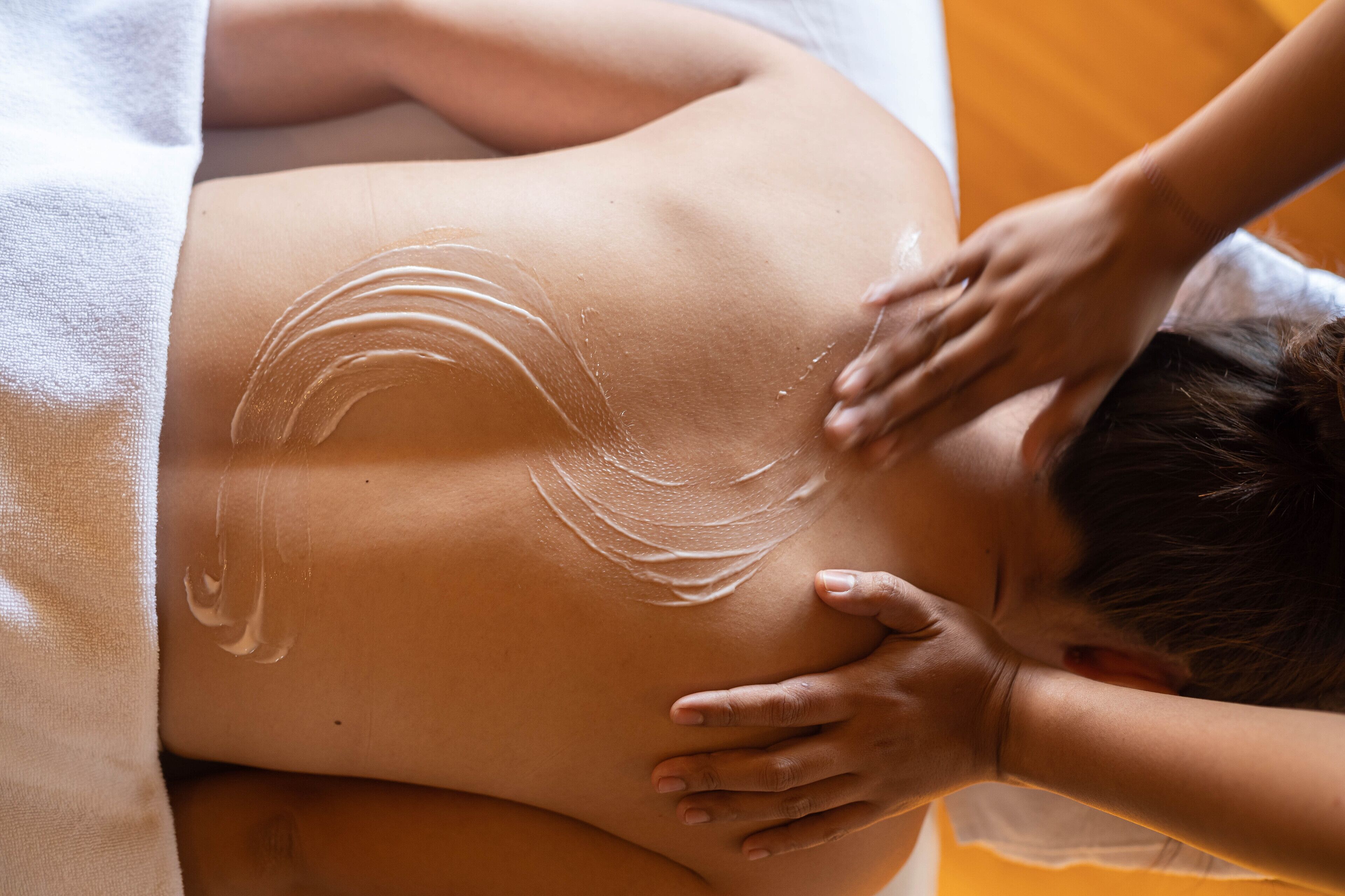 A person receiving a massage with visible oil on their back.
