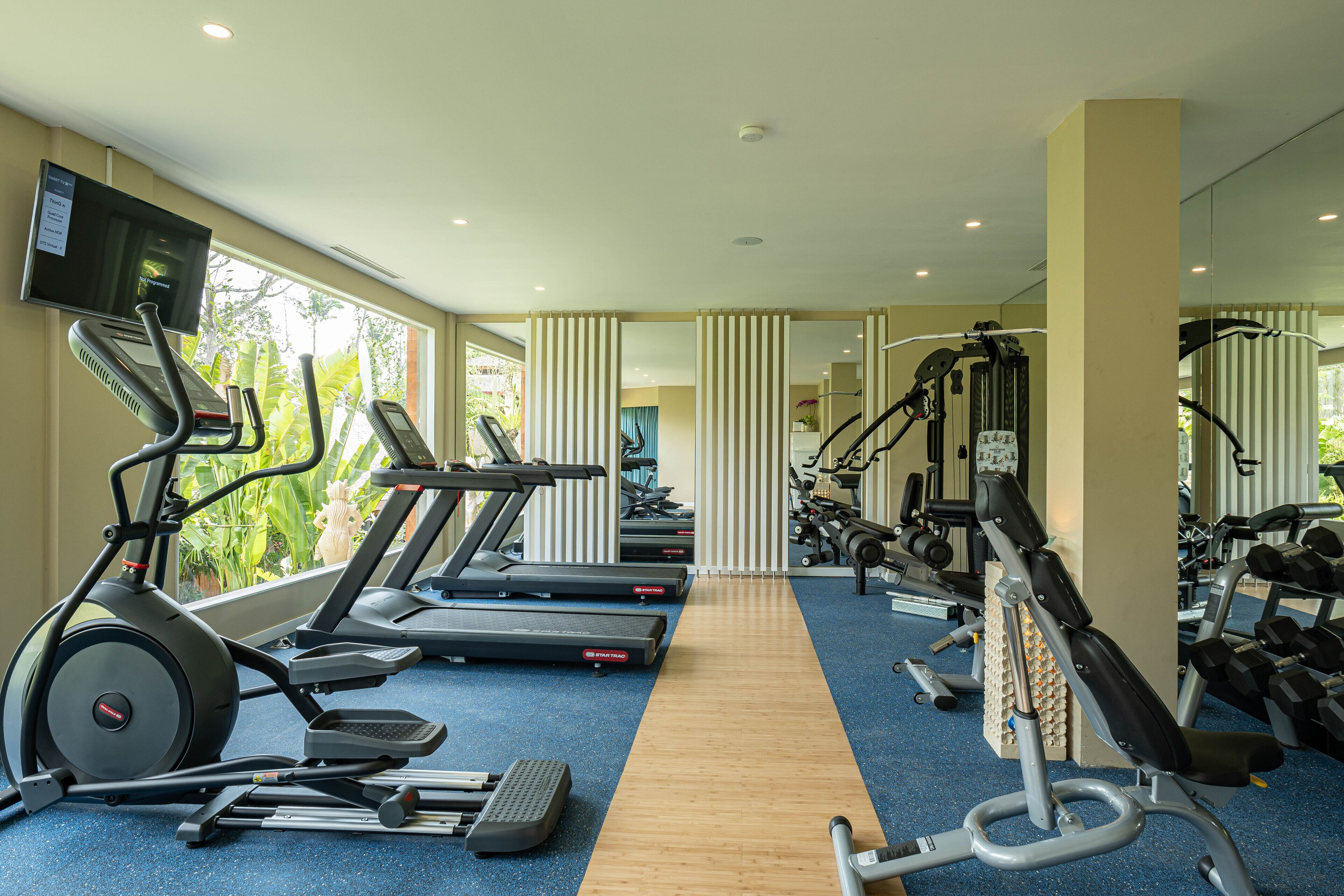 A gym with treadmills, elliptical machines, and weight equipment.