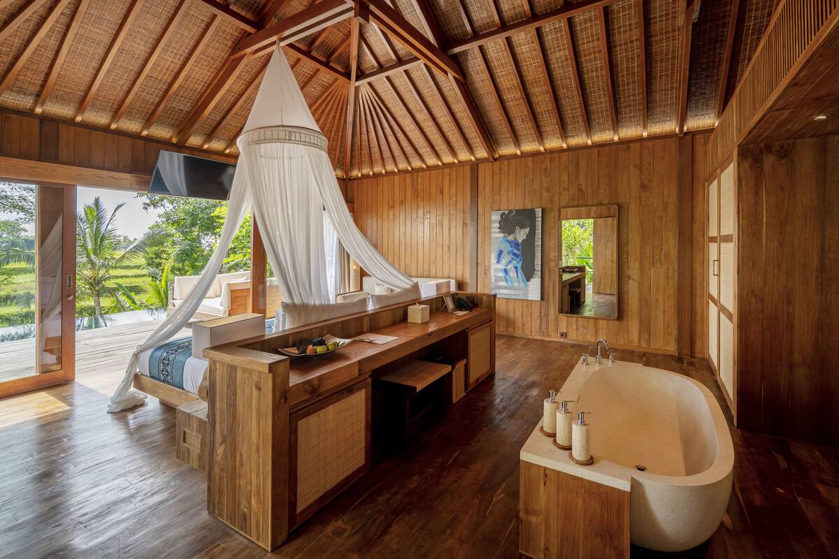 A wooden interior with a large bathtub, a vanity, and a bed with a canopy.